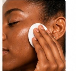 Woman using Exfoliating Glow Toner with a cotton pad